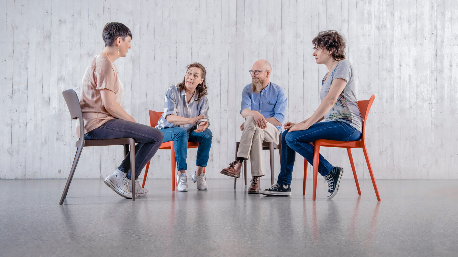 Drei Frauen und ein Mann sitzen in einer Runde und unterhalten sich